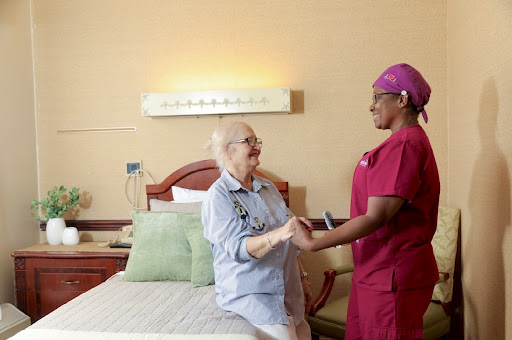A nurse provides care and support to an elderly patient in a hospital room.