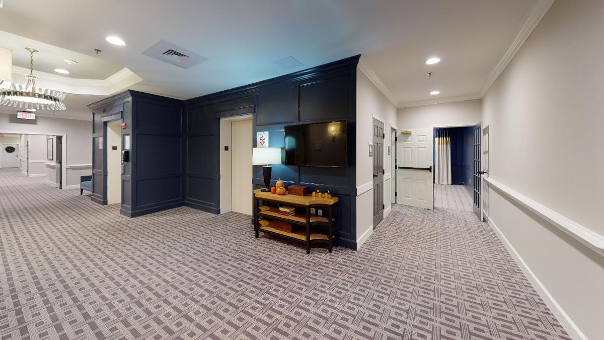 Modern lounge area with carpeted flooring and a wall-mounted television.