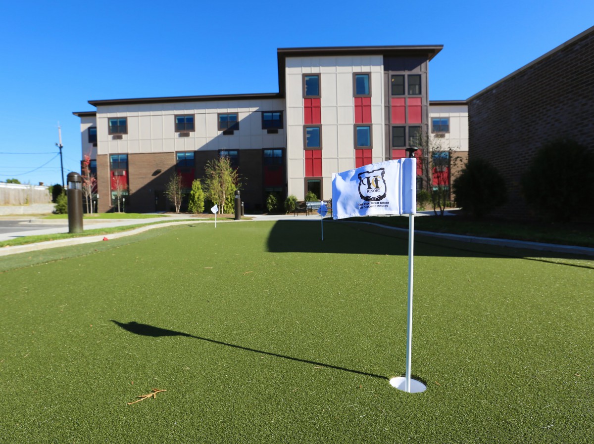 A modern building with a green lawn and a flag on a sunny day.