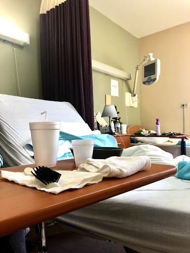 A view of a hospital room showing a bed, food and drink on the tray, and medical equipment in the background.