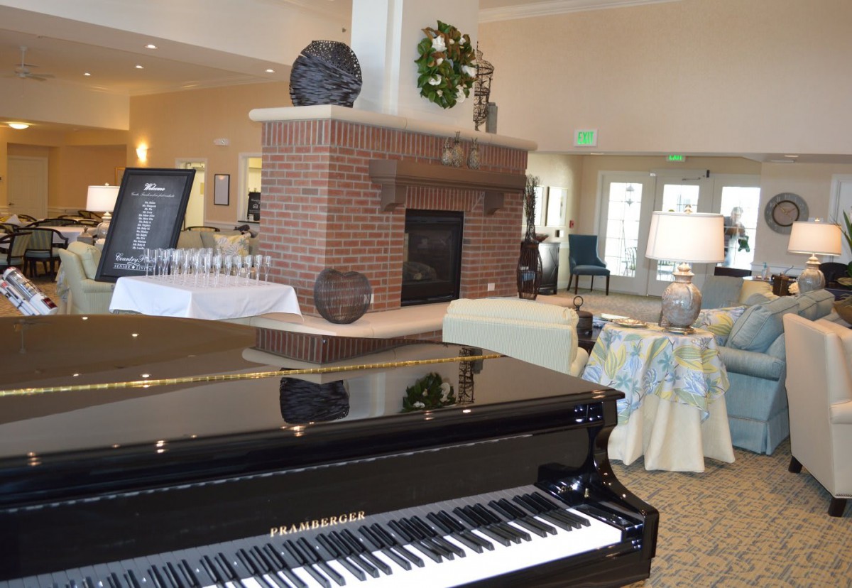 A cozy living room with a grand piano and brick fireplace.