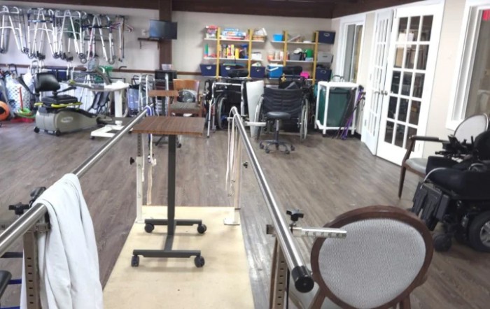 A well-equipped rehabilitation room featuring parallel bars and various therapy equipment.