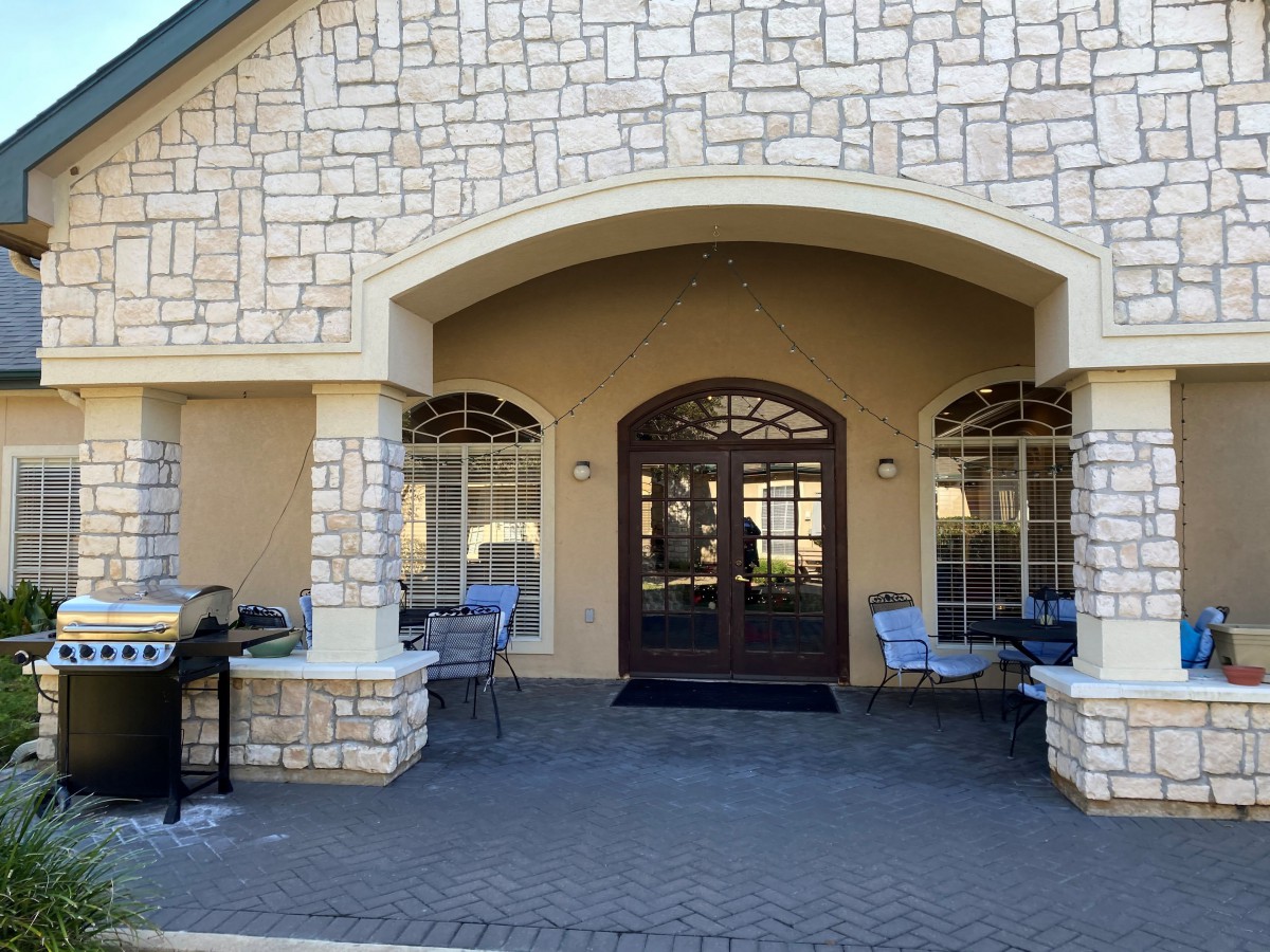 A building entrance with a stone facade, featuring an arched entryway and outdoor seating.