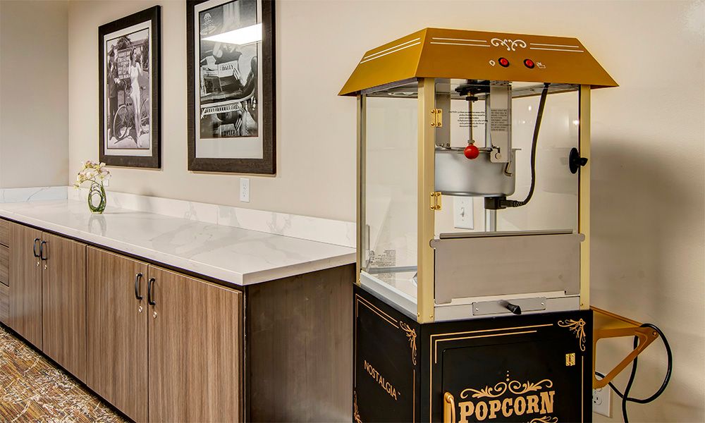A popcorn machine on a countertop in a room with framed pictures on the wall.