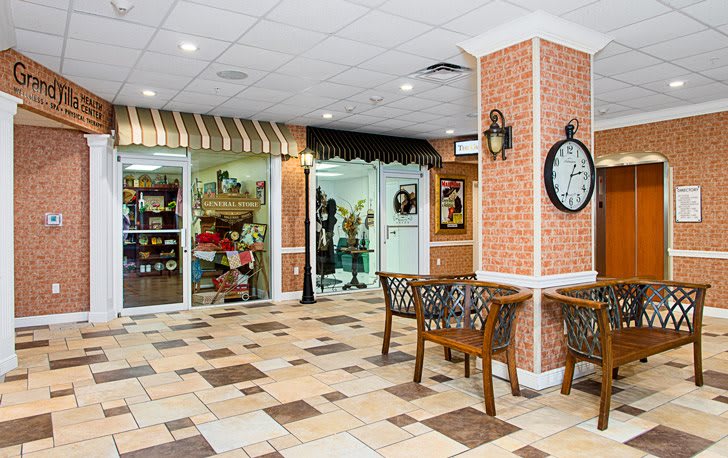 An interior view of a shopping center with storefronts, benches, and a clock on the wall.