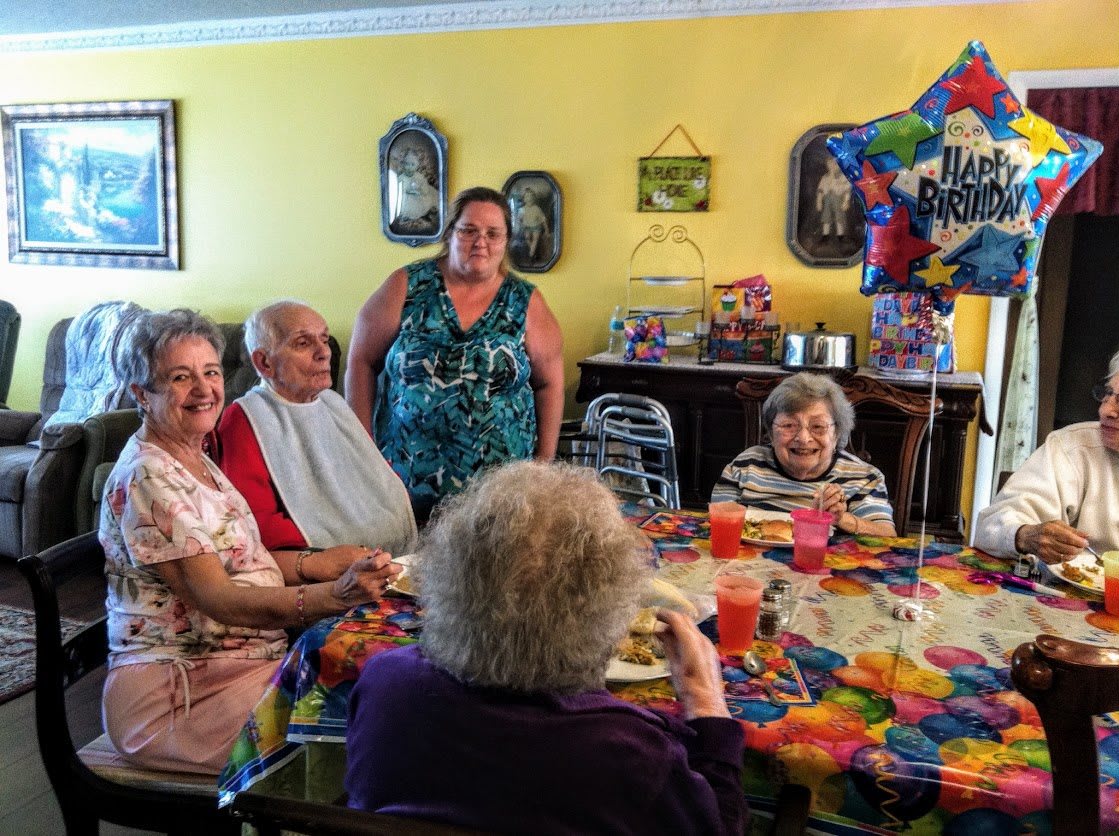 A family gathering with seniors celebrating around a decorated table.