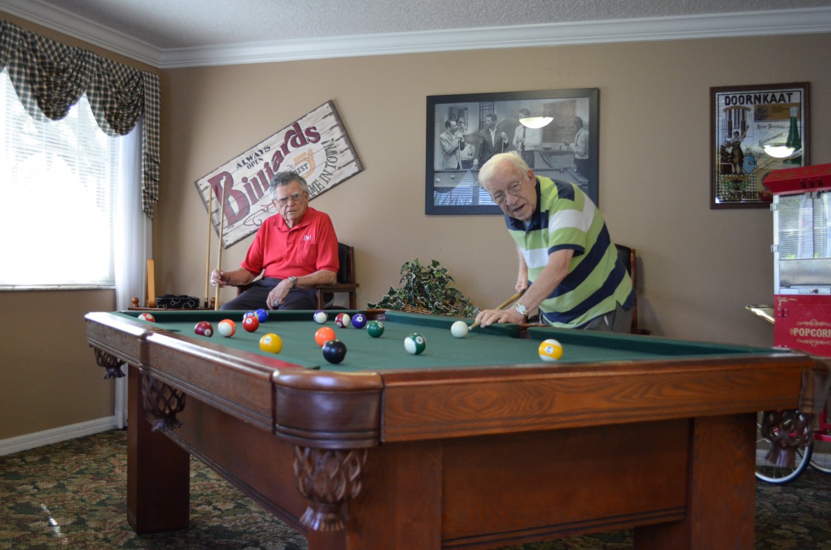 Two men playing a game of billiards in a cozy game room.