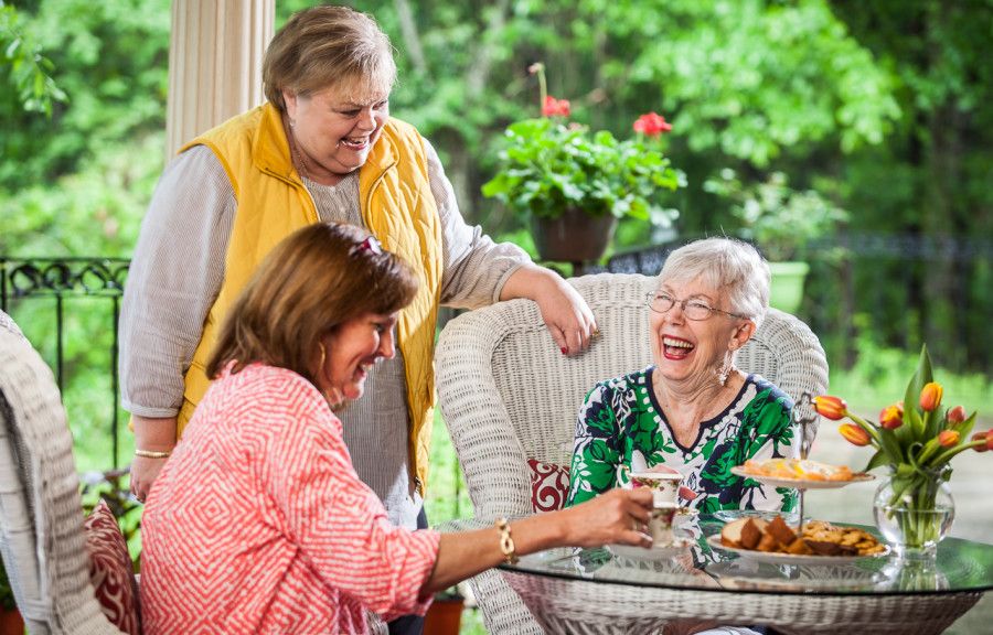 A group of senior women enjoying a lively conversation and laughter on a patio.