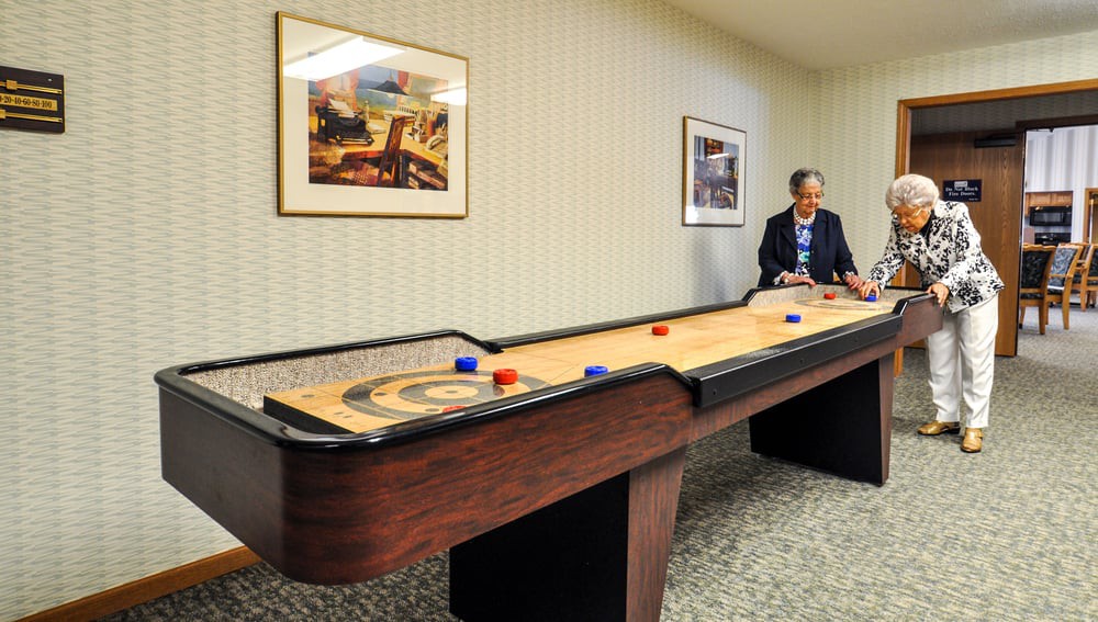 A person playing shuffleboard in a game room.