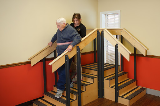 A caregiver assisting an elderly person as they navigate a set of stairs.