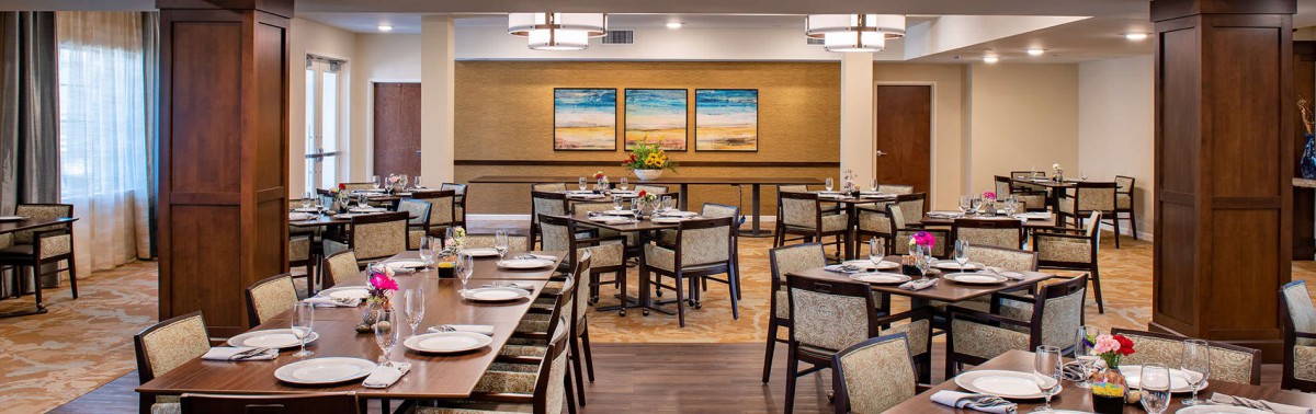 A well-decorated dining area with neatly arranged tables and chairs, featuring modern artwork on the walls.