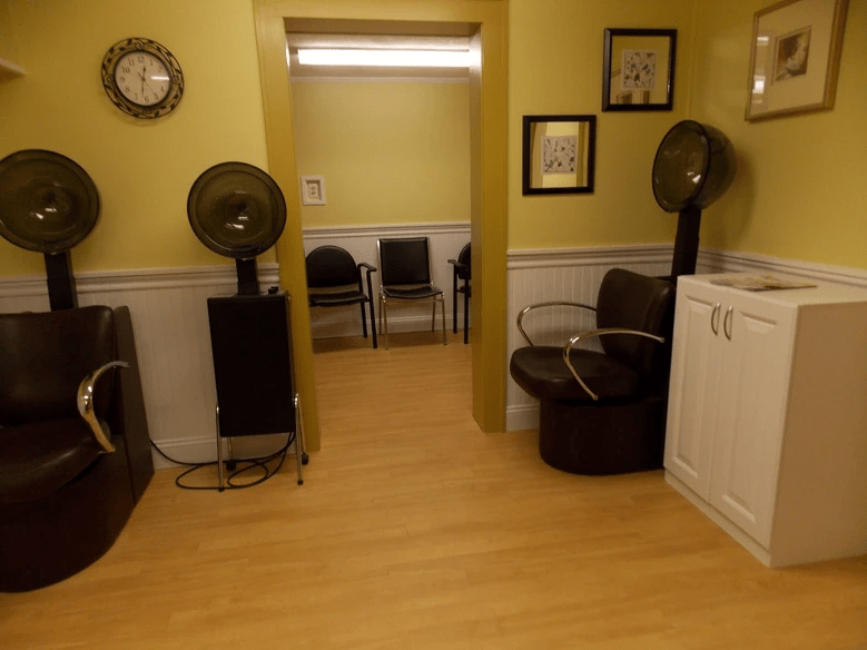 Interior view of a salon waiting area with hair dryers and seating.