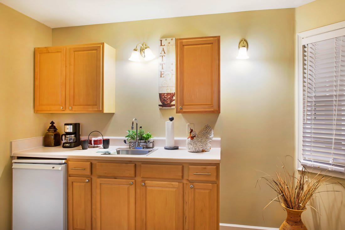A cozy kitchen corner with wooden cabinets, a coffee maker, and ambient lighting.