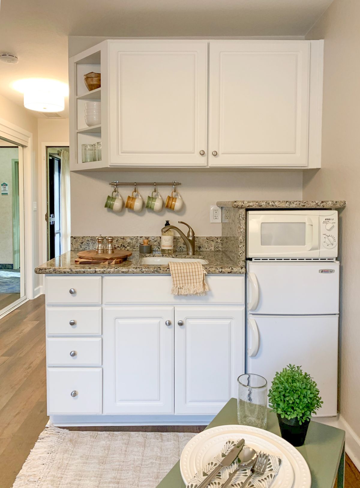 A compact kitchen space with white cabinets, a granite countertop, and essential appliances.