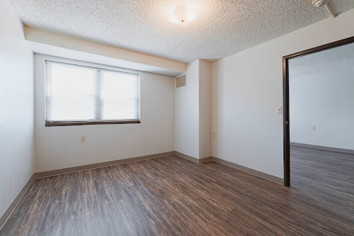 A spacious, empty room with natural light coming in through the window and a door leading to another area.