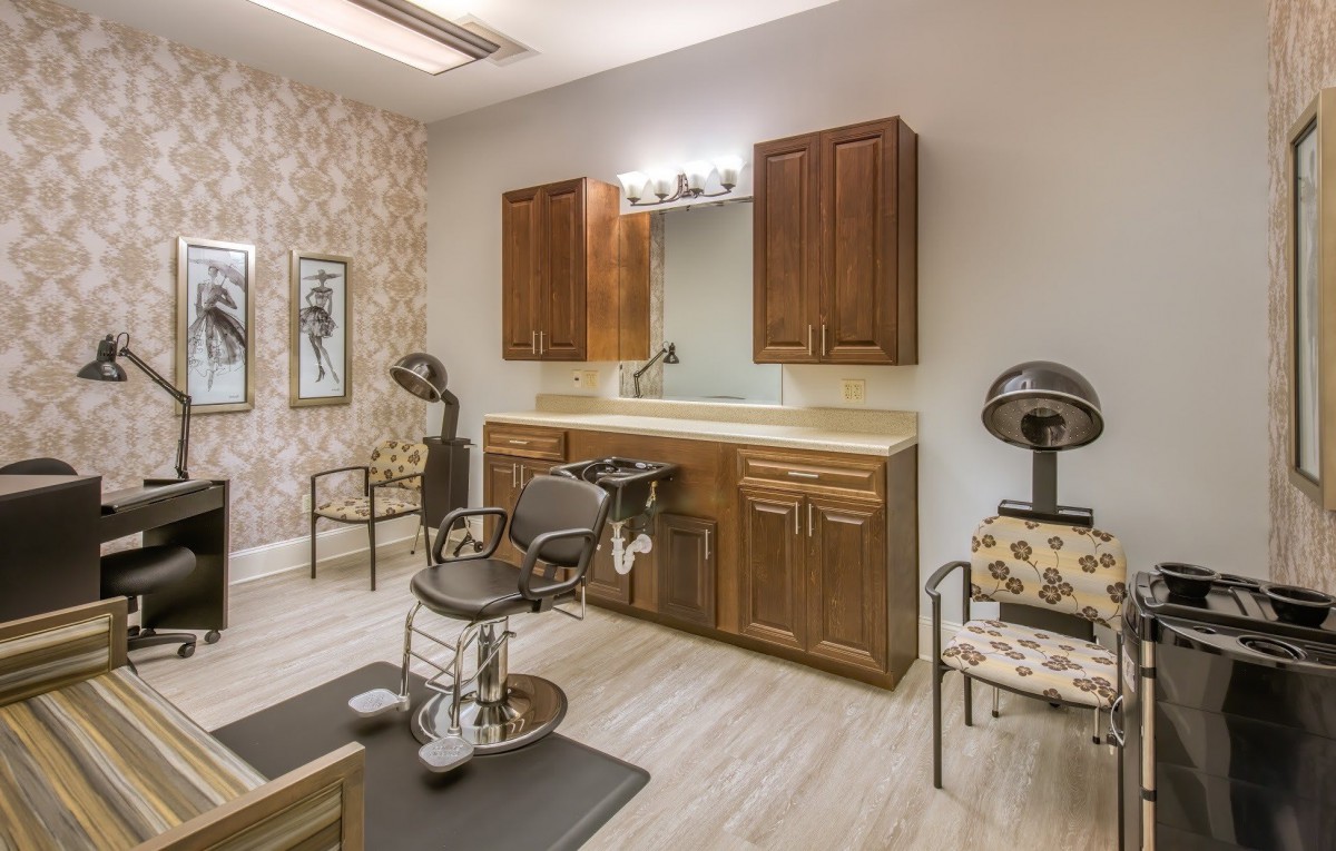 A well-organized hair salon interior featuring a styling chair, mirror, and cabinets.