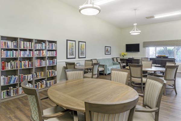 A modern library reading room with bookshelves, tables, and chairs.