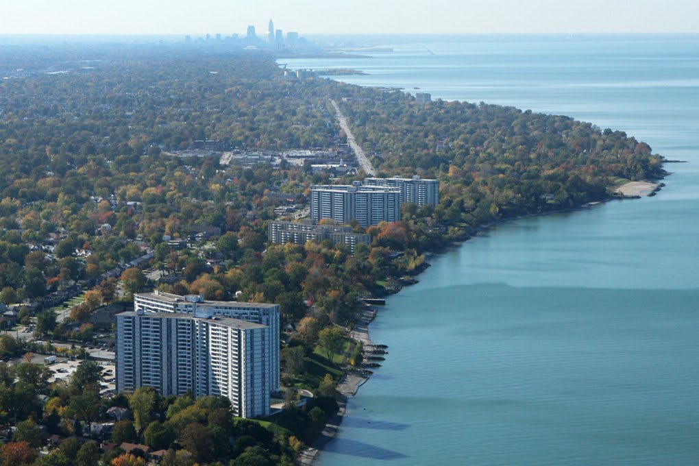 Aerial view of a city along a lakefront with buildings and distant skyline.