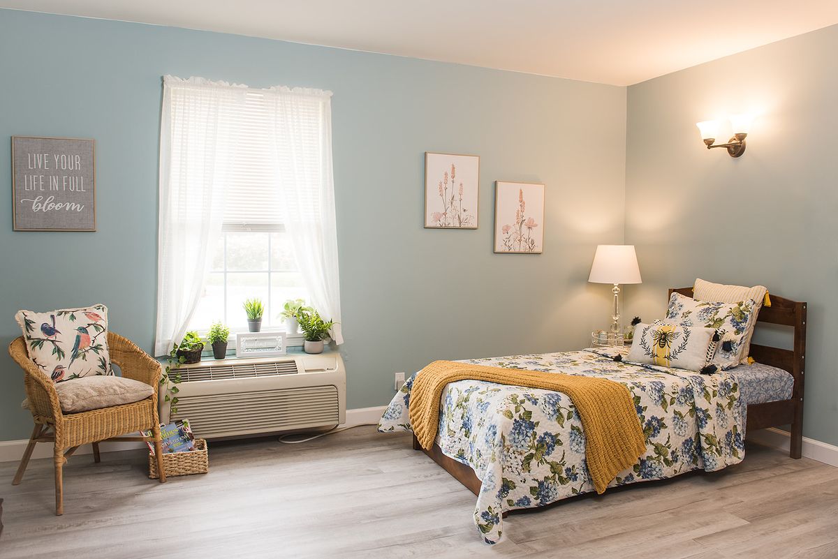 A cozy bedroom with blue walls, a floral bedspread, and soft lighting.