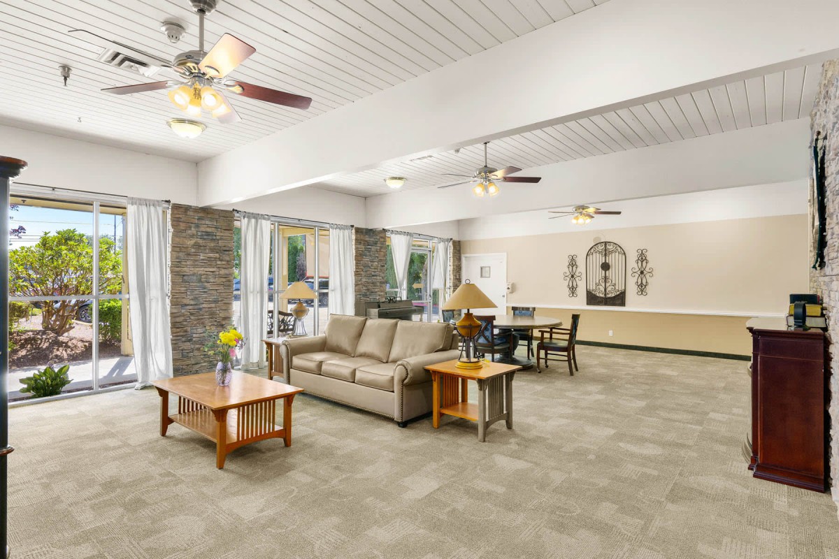 A spacious living room with modern furniture and ceiling fans.