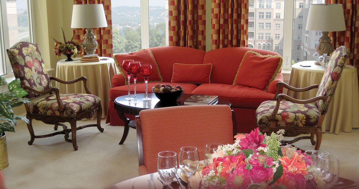 A cozy living room with a red sofa, a coffee table, and floral decor.