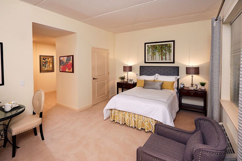 A well-decorated hotel room featuring a comfortable bed, bedside tables with lamps, and framed artwork on the walls.