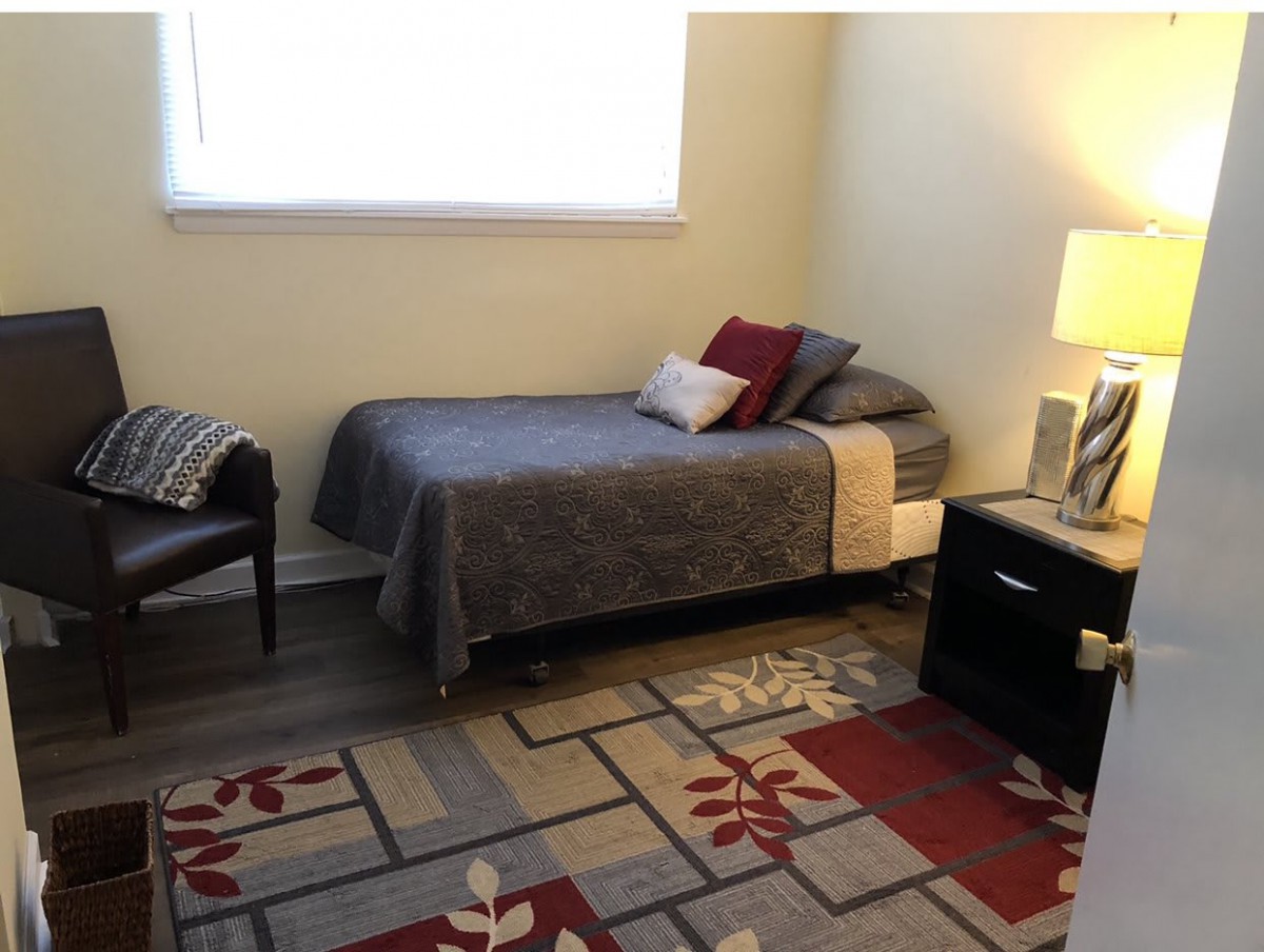 A cozy bedroom with a single bed, nightstand, and decorative rug.