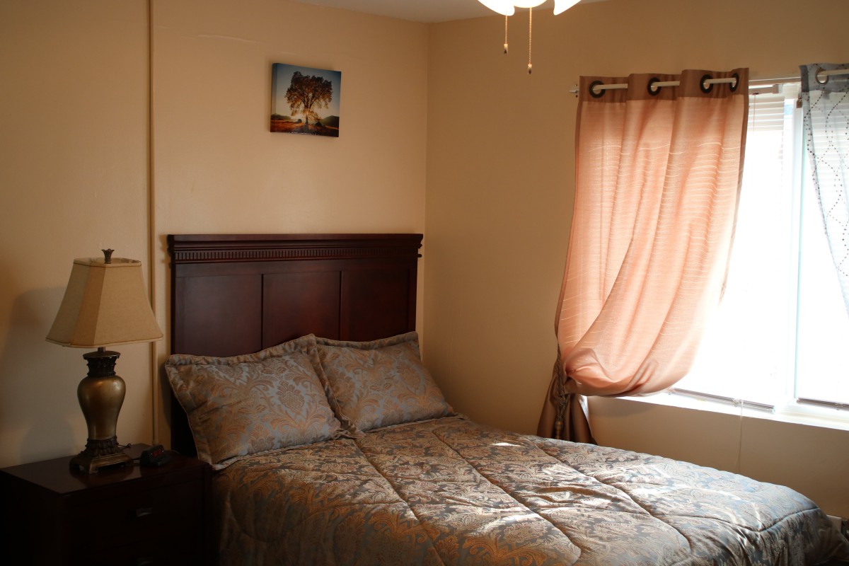 Cozy bedroom with a bed, decorative pillows, and a window with curtains.
