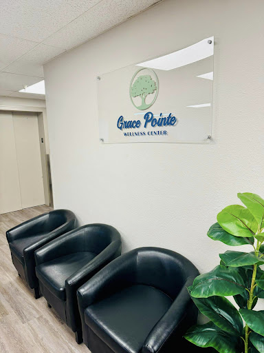 A modern waiting area featuring black chairs and a sign for 'Green Pointe' along with indoor plants.