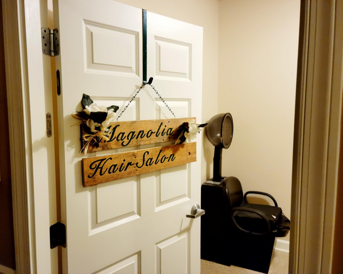 An interior view of a hair salon with a wooden sign on the door.