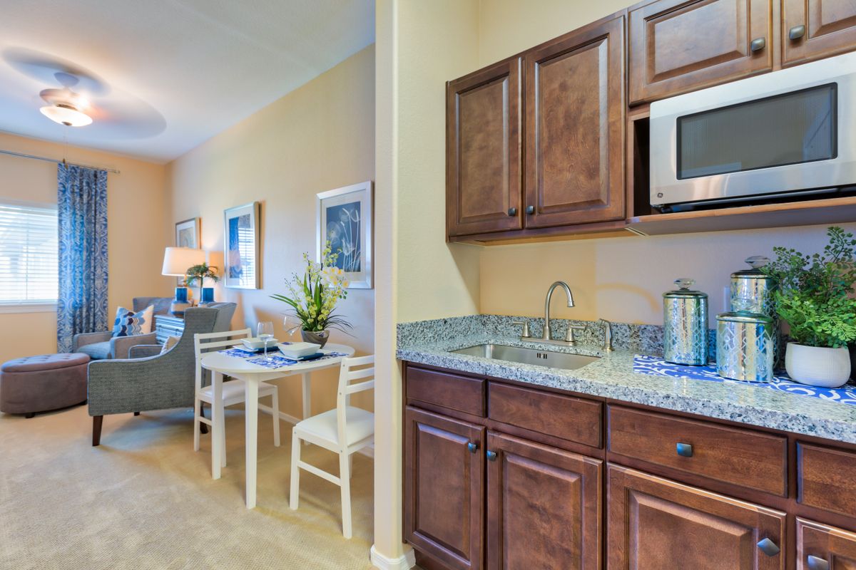 A cozy apartment kitchen with wooden cabinets and a small dining area.