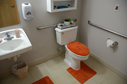 A neatly organized bathroom featuring an orange-themed toilet and floor mats.