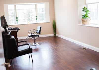 A minimalist salon interior with chairs and a wooden floor.
