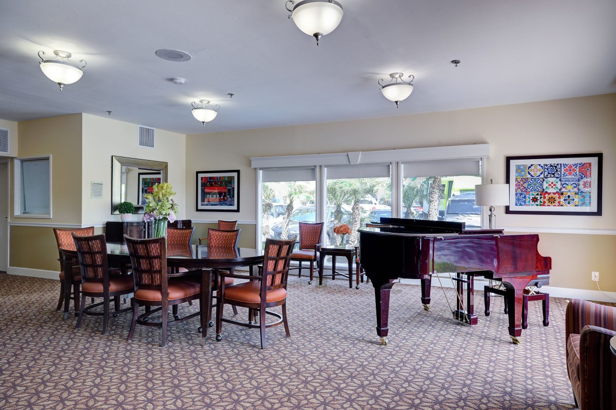 A well-furnished lounge with dining tables, chairs, and a piano.