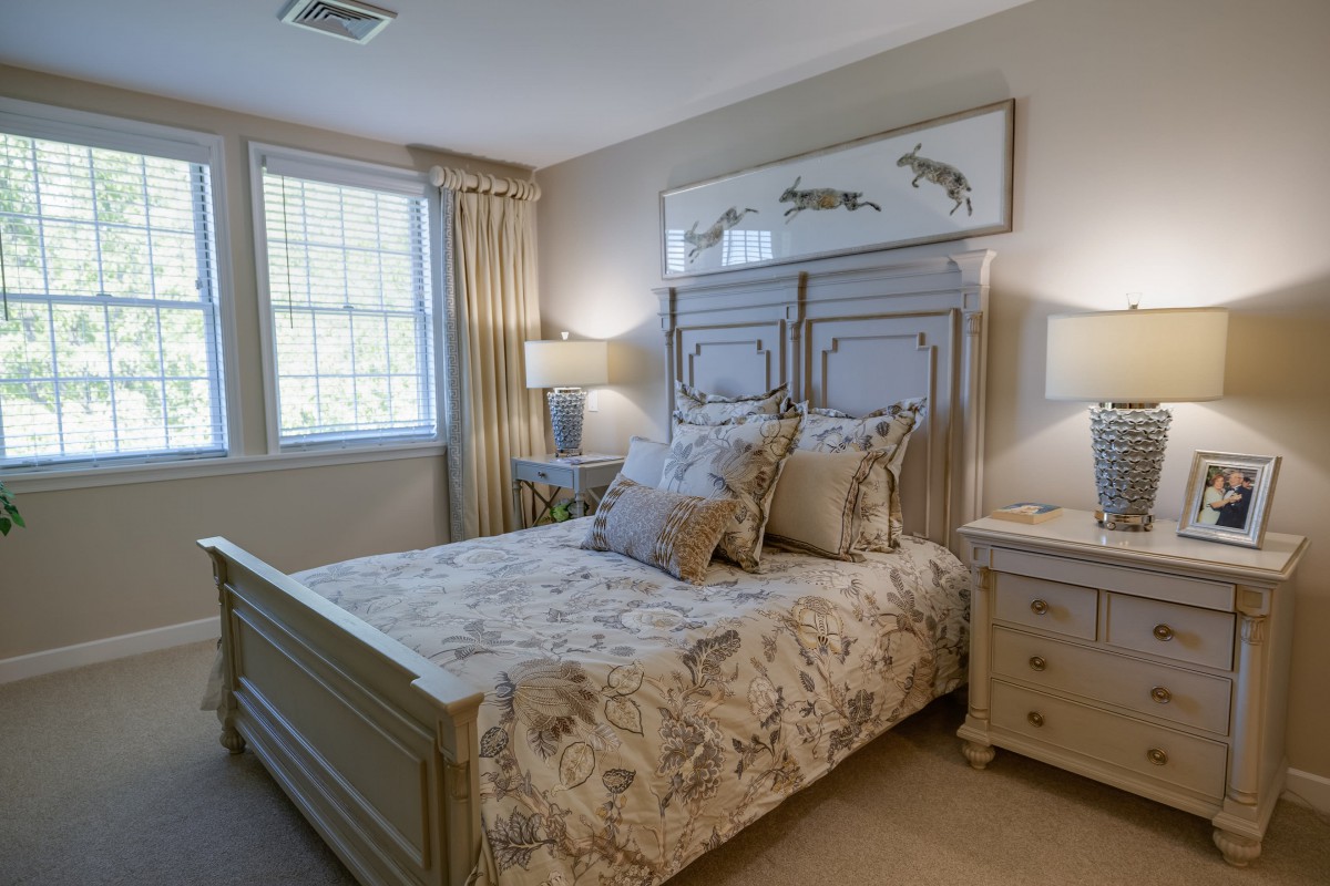 A cozy bedroom with a stylish double bed, complemented by matching nightstands and lamps, featuring floral bedding and elegant decor.