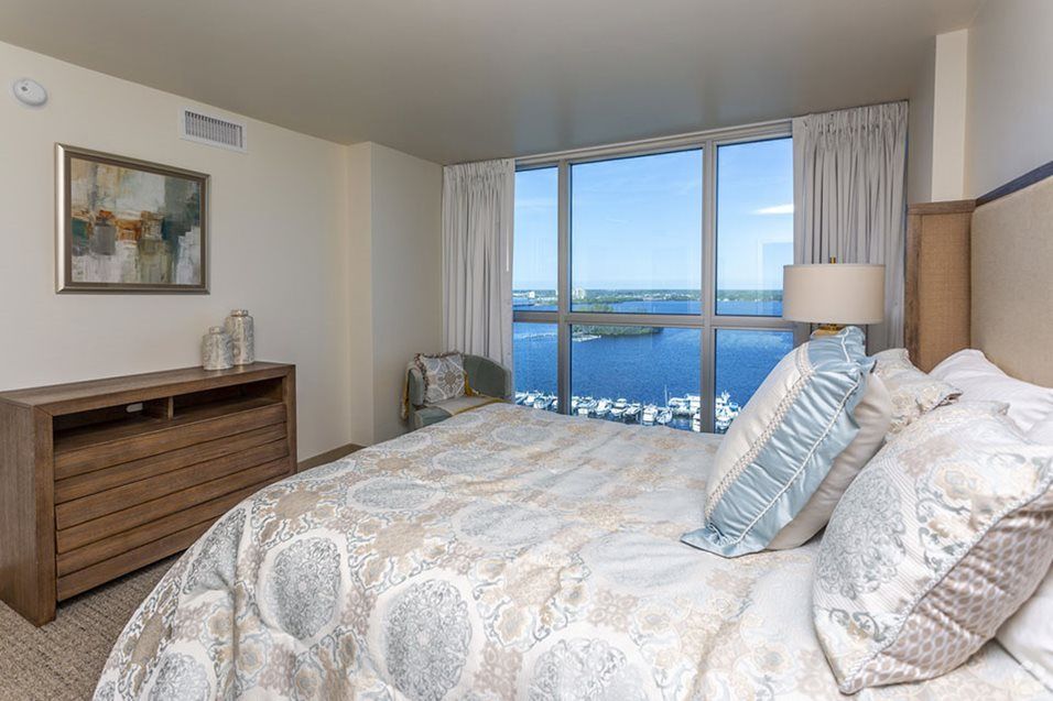 A cozy bedroom with a large window offering a stunning ocean view.