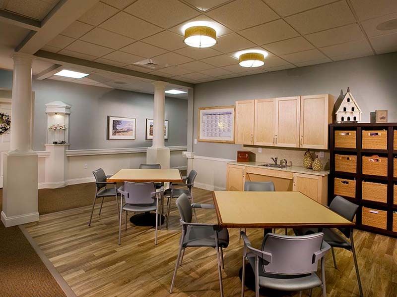 A modern kitchen and dining area with wooden flooring, tables, chairs, and cabinetry.