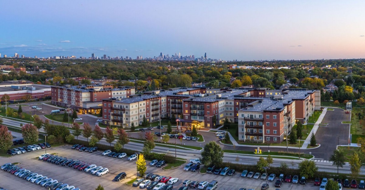 Aerial view of apartment buildings with a city skyline in the background during the evening.