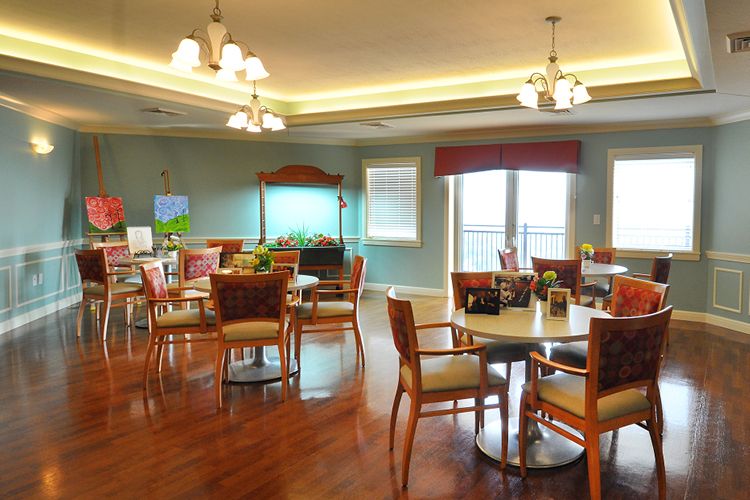 A well-lit dining area featuring multiple tables and chairs, with elegant lighting fixtures and hardwood flooring.