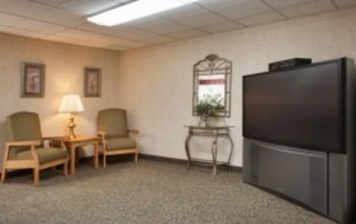 A cozy living room with a television, chair, lamp, and decorative elements.