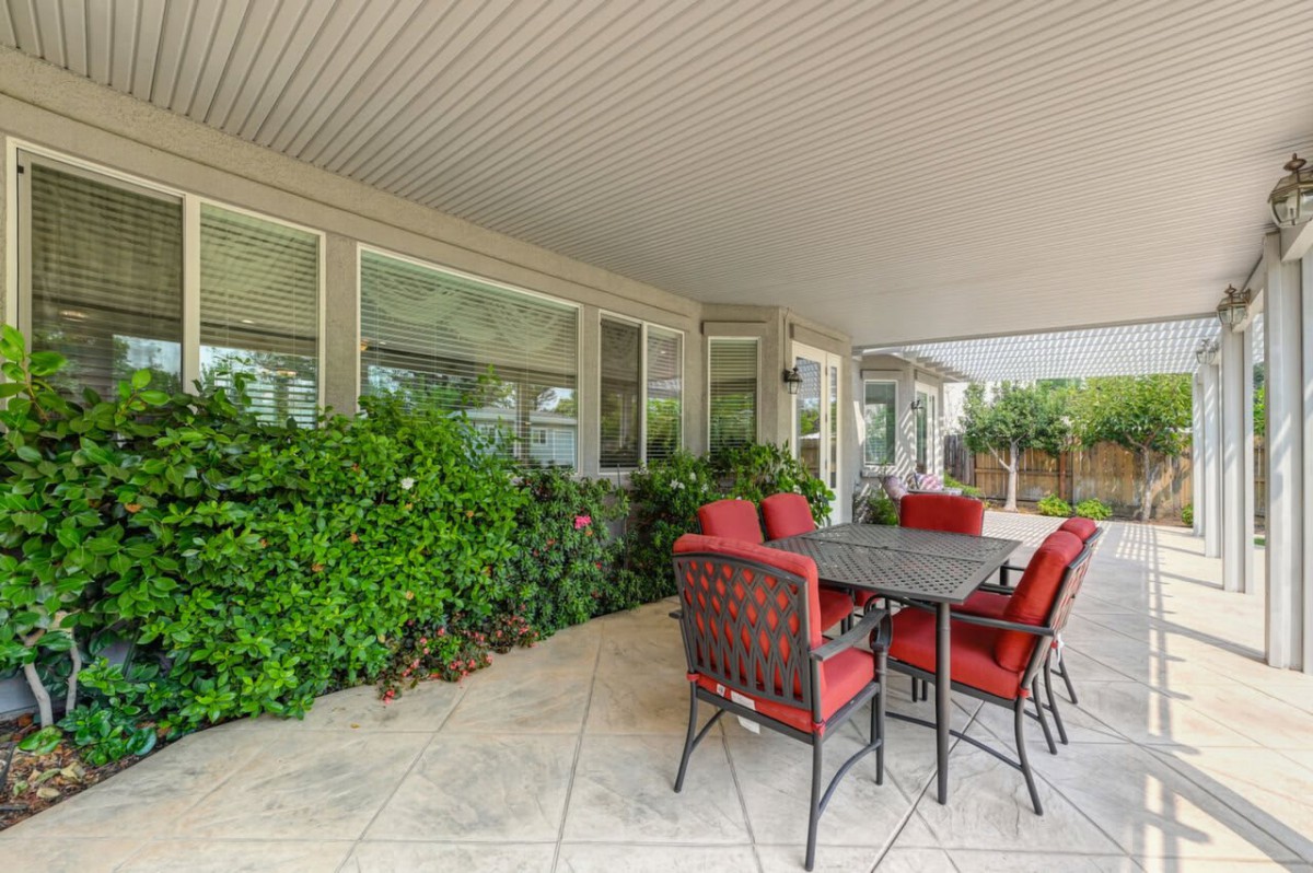 A cozy outdoor patio area with a table, chairs, and surrounding greenery.