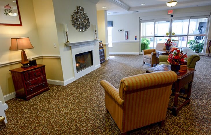 A cozy living room with a fireplace, armchair, and carpeted floor.