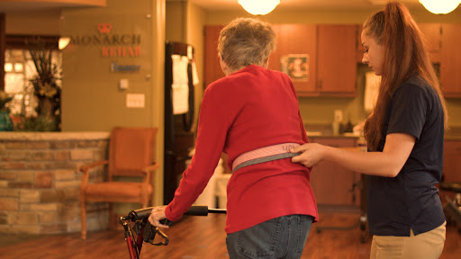 An elderly person is being assisted while using a walking aid in an indoor setting.