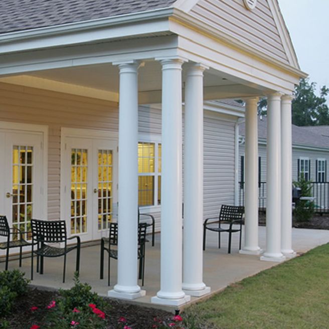 A building with a covered porch featuring columns and outdoor seating.