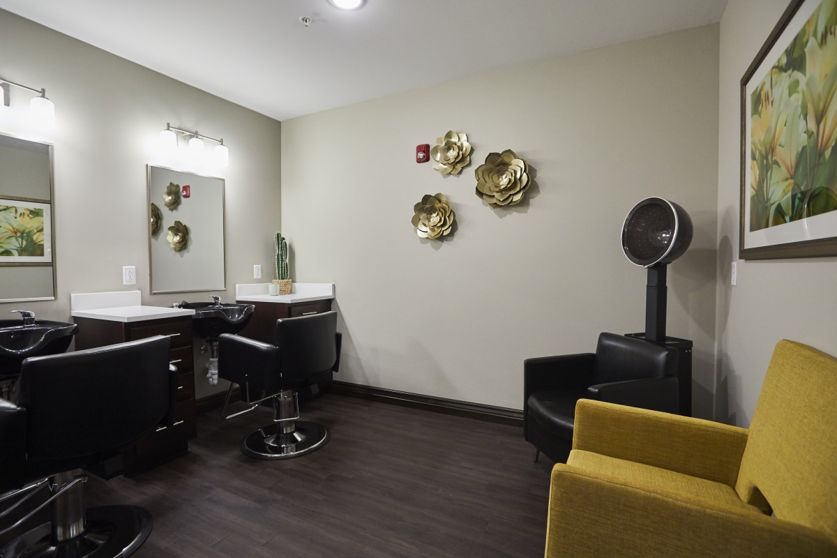 A modern salon interior with styling chairs, a hair dryer, and decorative wall art.