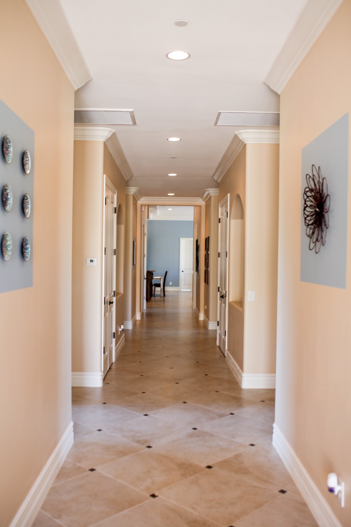 A modern hallway adorned with contemporary artwork and leading to a distant room.