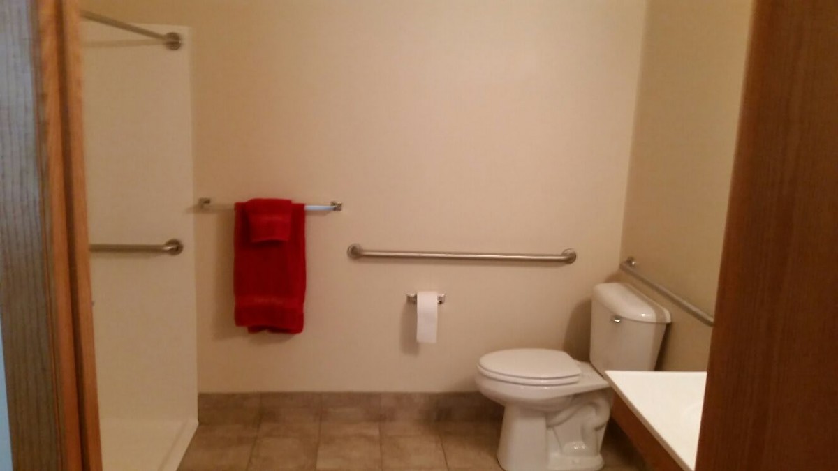 An accessible bathroom with a toilet, red towel, and grab bar.