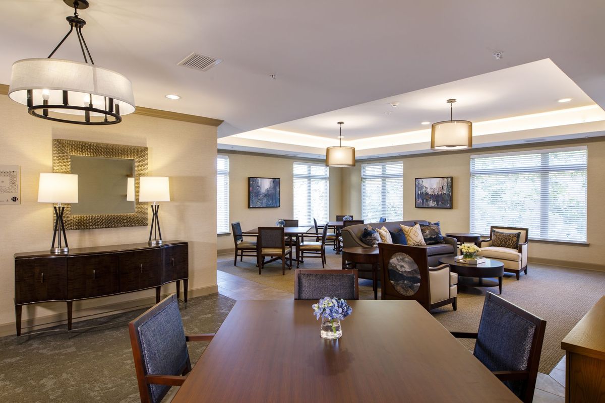 A modern and spacious living area featuring a dining table, comfortable seating, and elegant lighting.
