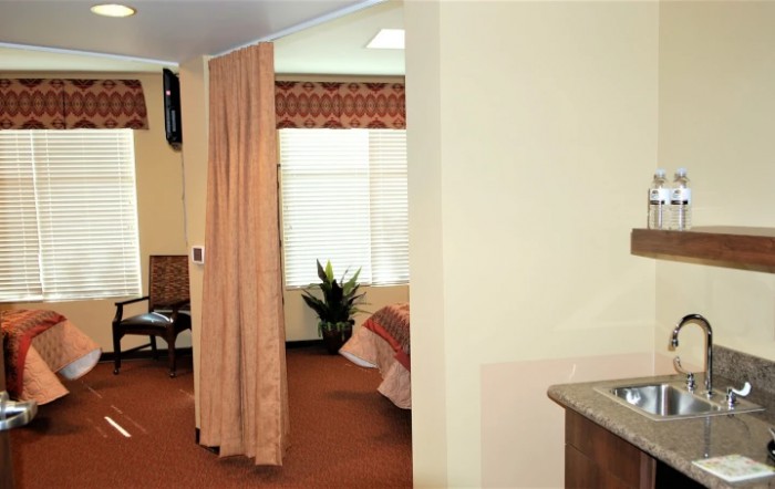A hospital room with a curtain divider and a bed near the window.