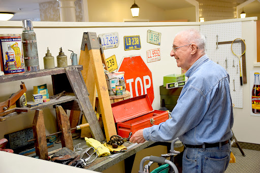 A man organizes tools and vintage items in a workshop setting.